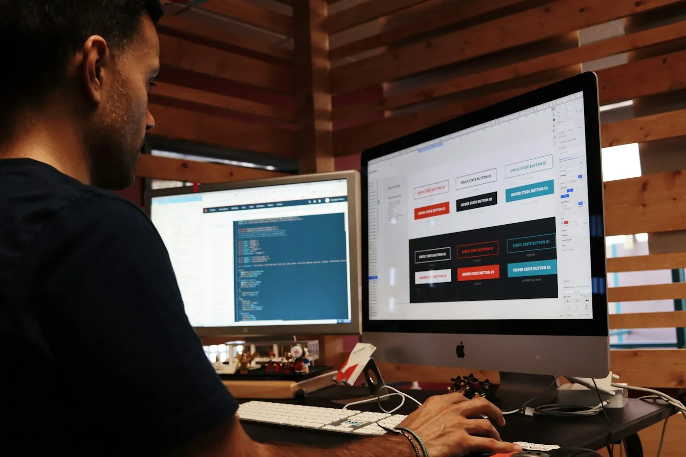 Designer reviewing website interface components and code on two desktop screens